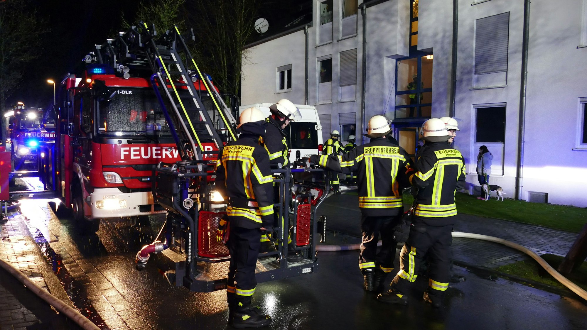 Feuerwehrleute stehen vor einem Haus.
