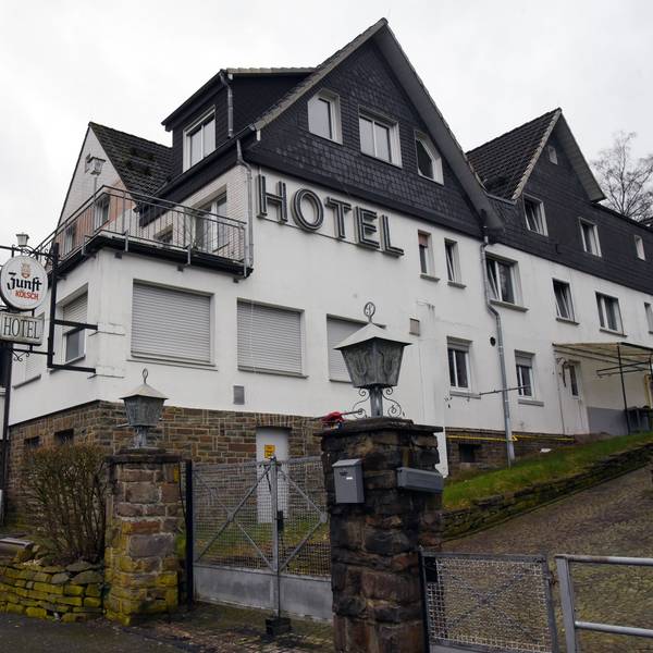 Ein großes Haus mit verschlossenen Fenstern und heruntergelassenen Rollläden steht an einer Straße, auf der Fassade ist der Schriftzug „Hotel“ zu lesen.