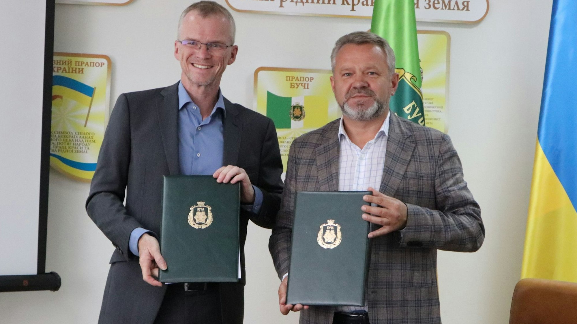 Bergisch Gladbachs Bürgermeister Frank Stein und Butschas Bürgermeister Anatolii Fedoruk halten Mappen mit der unterschrieben Städtepartnerschaftsurkunde in den Händen.
