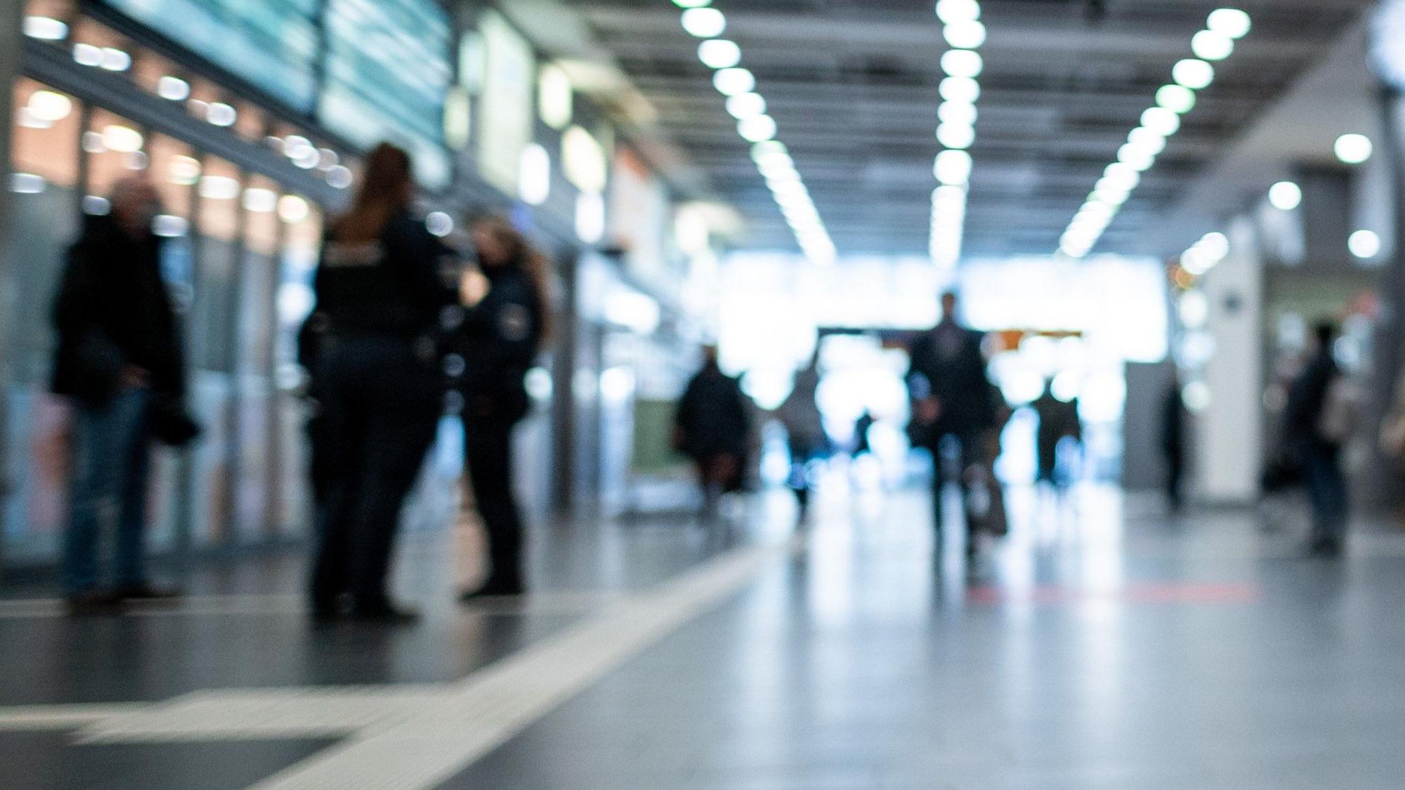 Polizisten kontrollieren Personen an einem Bahnhof.