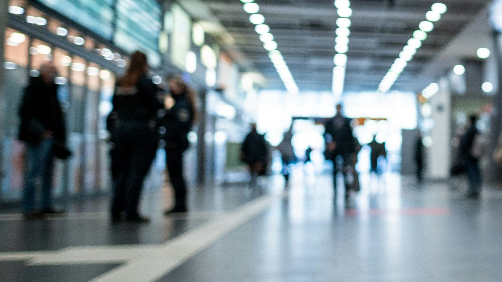 Polizisten kontrollieren Personen an einem Bahnhof.