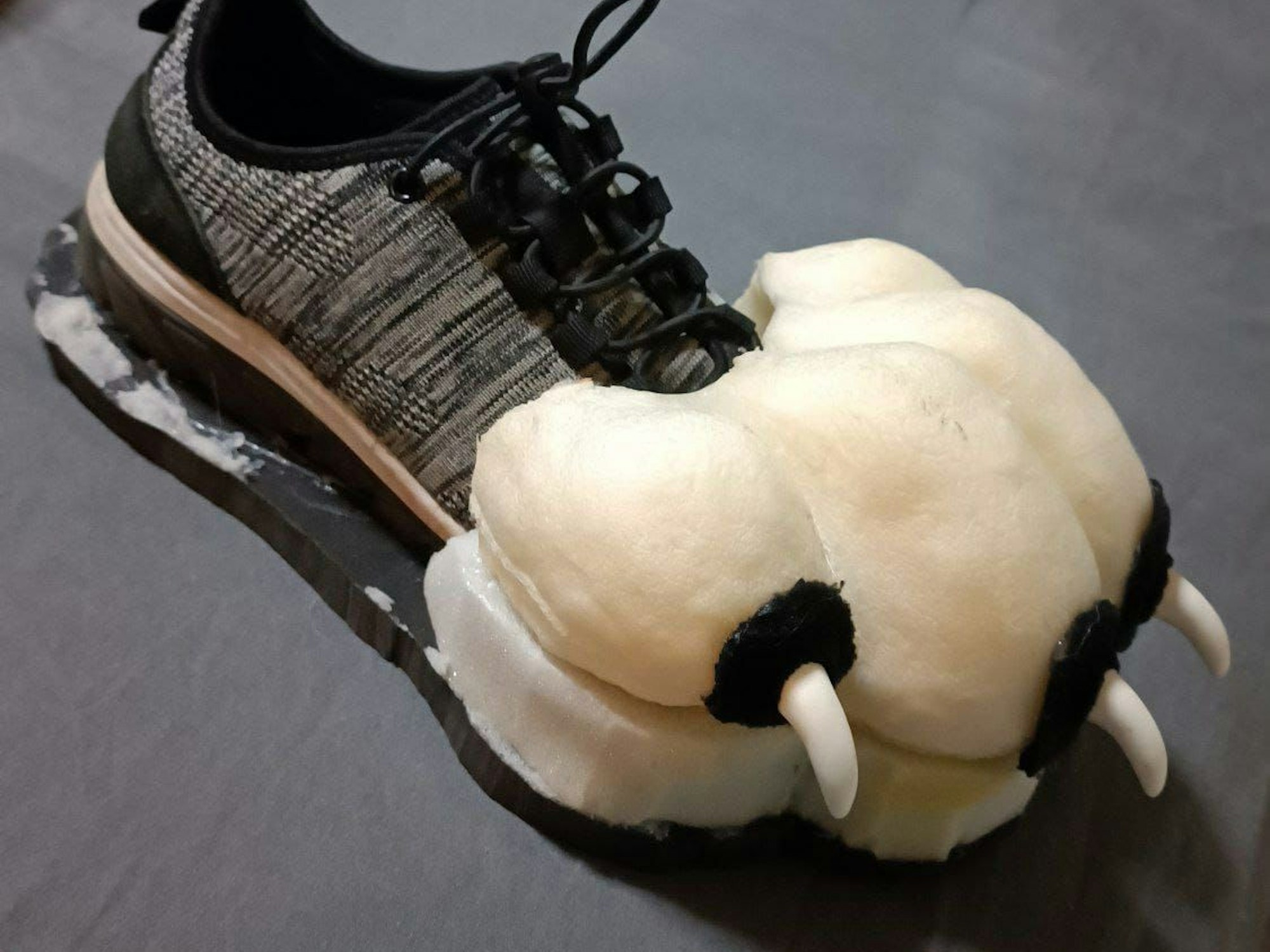 Auf Turnschuhen sind plüschige Tatzen mit Krallen daran angebracht.