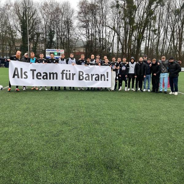 Die Spieler des SSV Jan Wellem halten ein Banner mit der Aufschrift "Als Team für Baran!" hoch