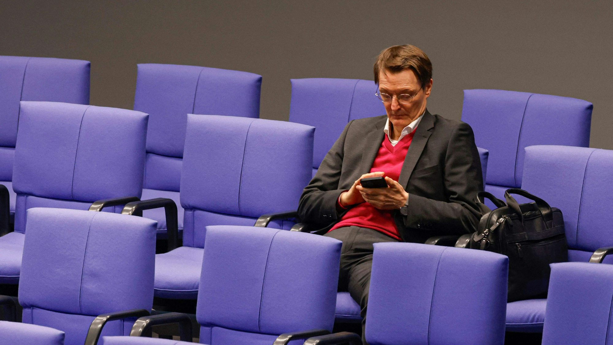 Gesundheitsminister Karl Lauterbach sitzt und wartet auf das Ergebnis.