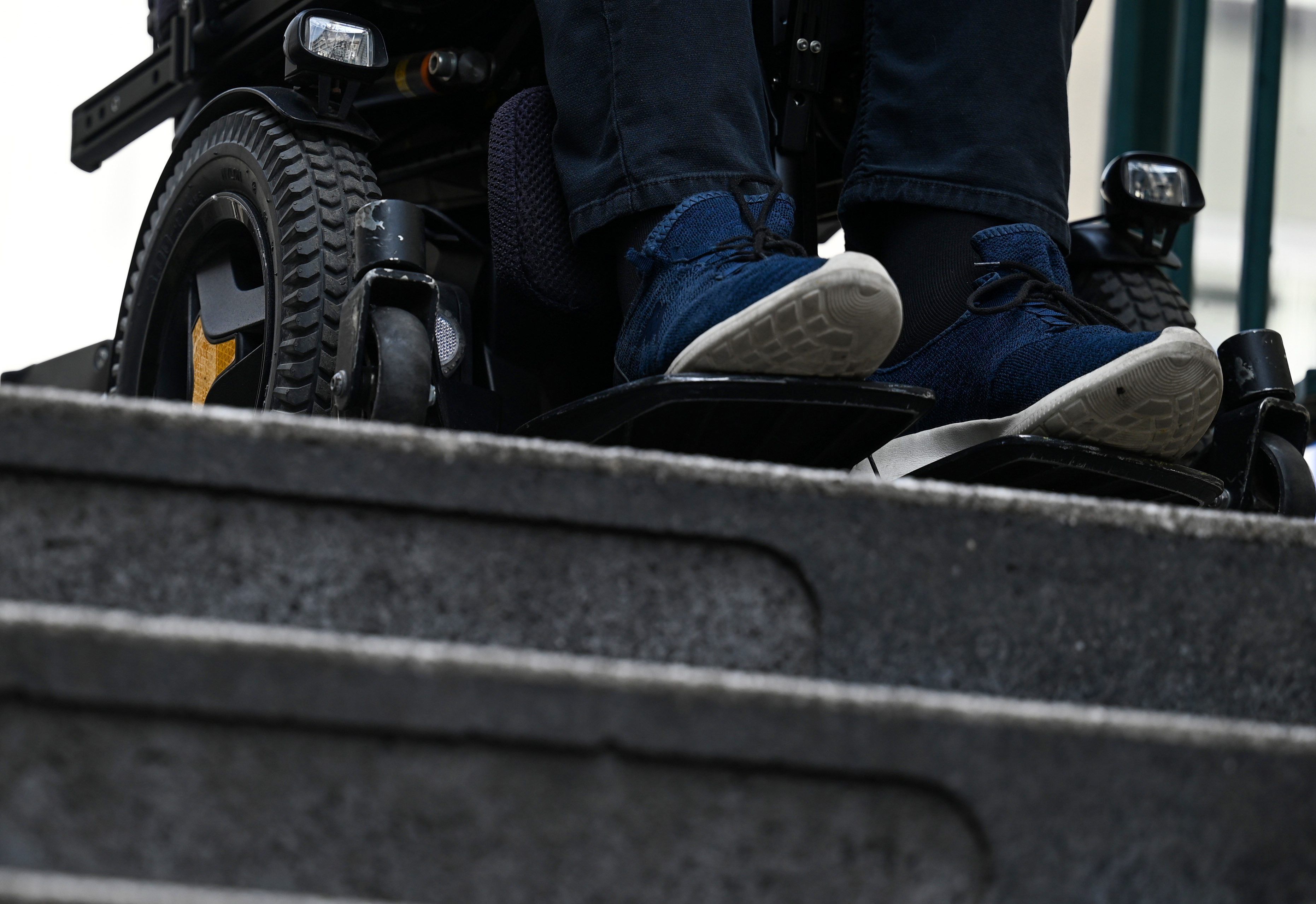 Ein Mann steht mit seinem Rollstuhl vor der Treppe eines Eingangs zur U-Bahn.