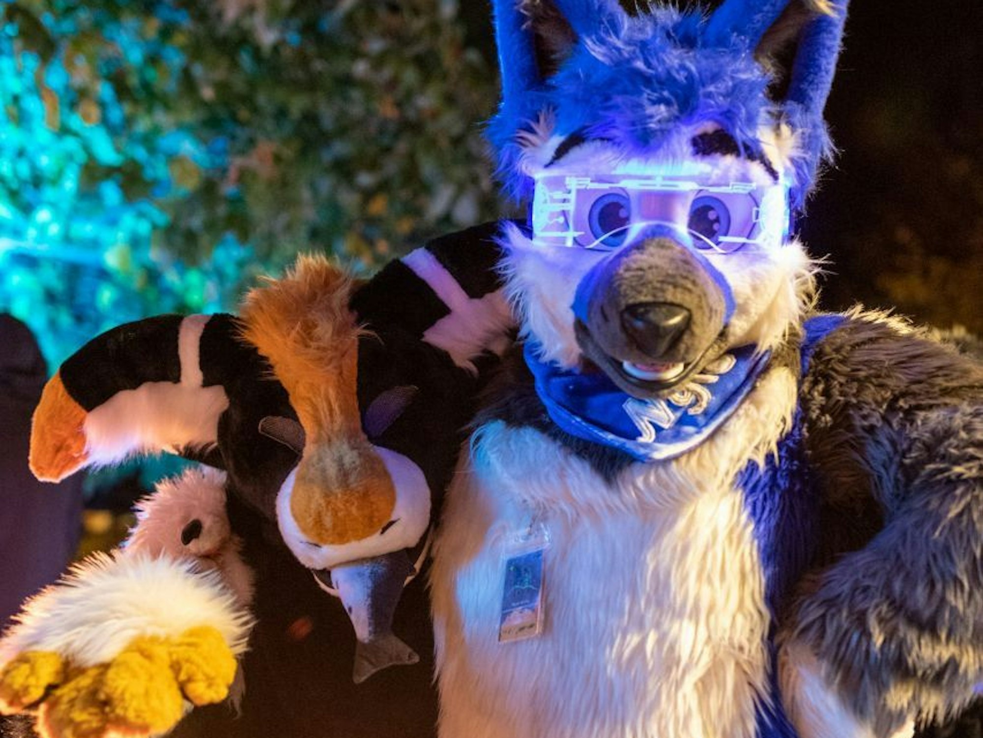 Ein plüschiger Manokin und ein plüschiger Wolf, der eine LED-Sonnenbrille trägt, halten sich im Arm.