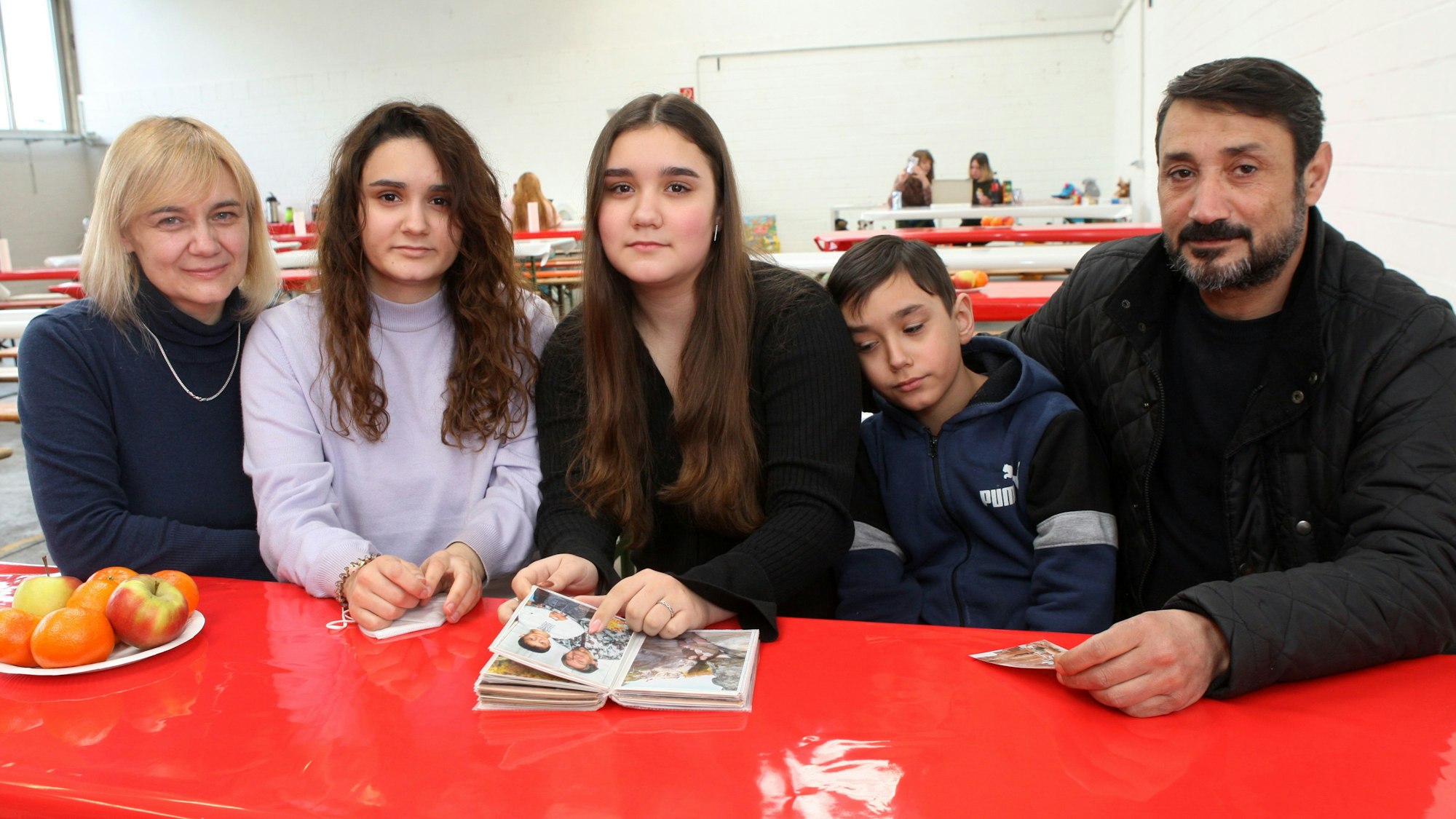 Eine Familie sitzt mit einem Fotoalbum an einem Tisch in einer Erstaufnahmeeinrichtung für Geflüchtete in Bergisch Gladbach.