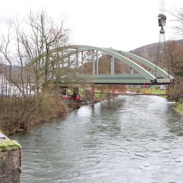 Eine Stahlbrücke mit Bogen über einem Fluss.