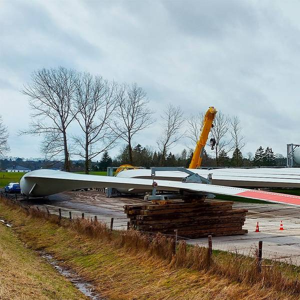 Rotorblätter lagern auf einer Wiese.