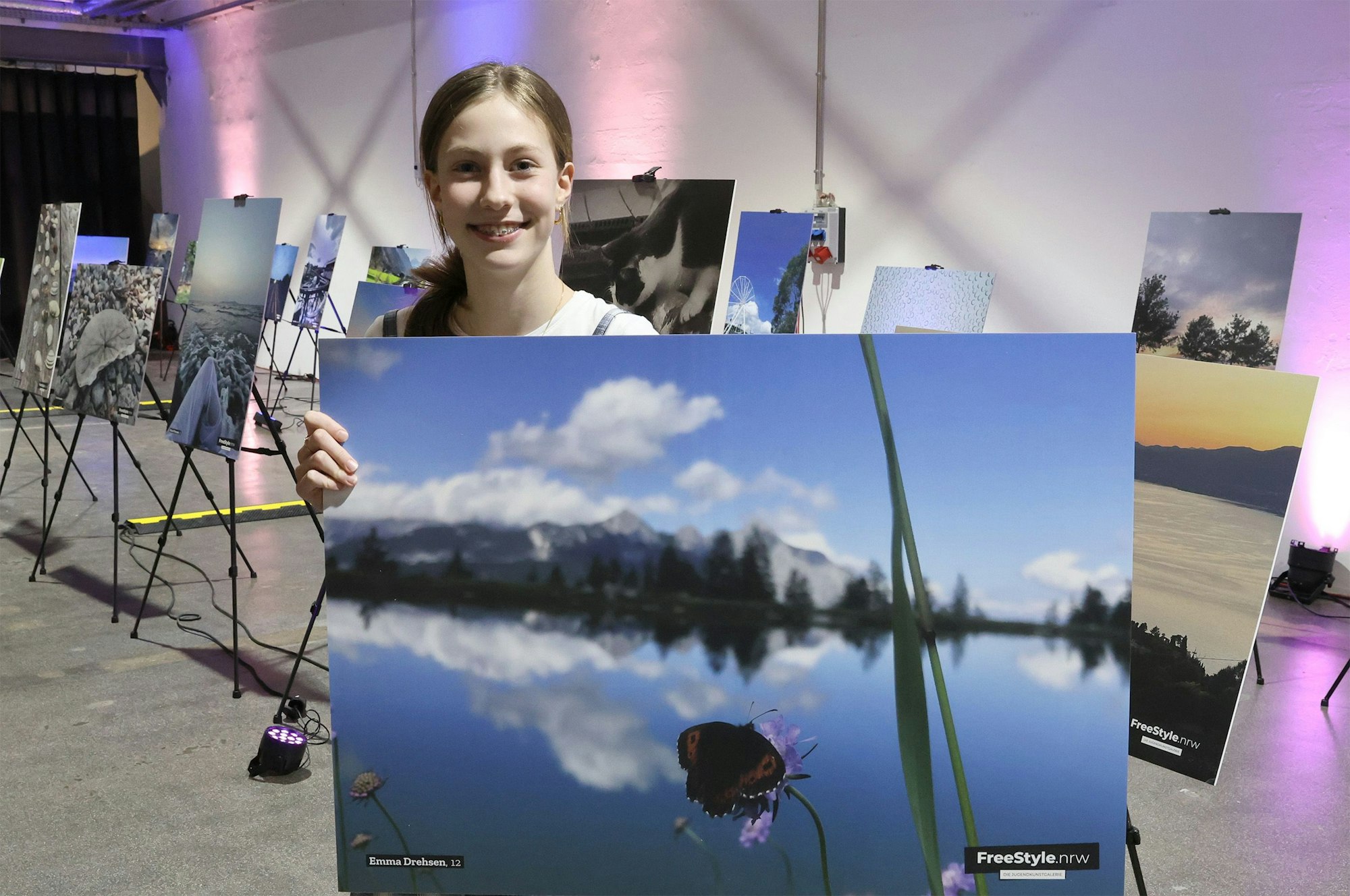Emma Drehsen posiert mit einem Foto auf dem eine Berglandschaft zu sehen ist.