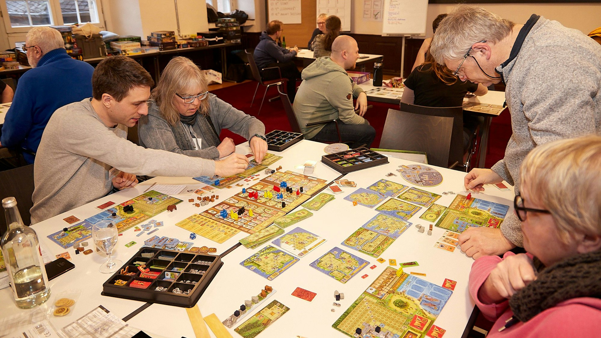 Das Bild zeigt vier Menschen, die sich ein Brettspiel erklären.