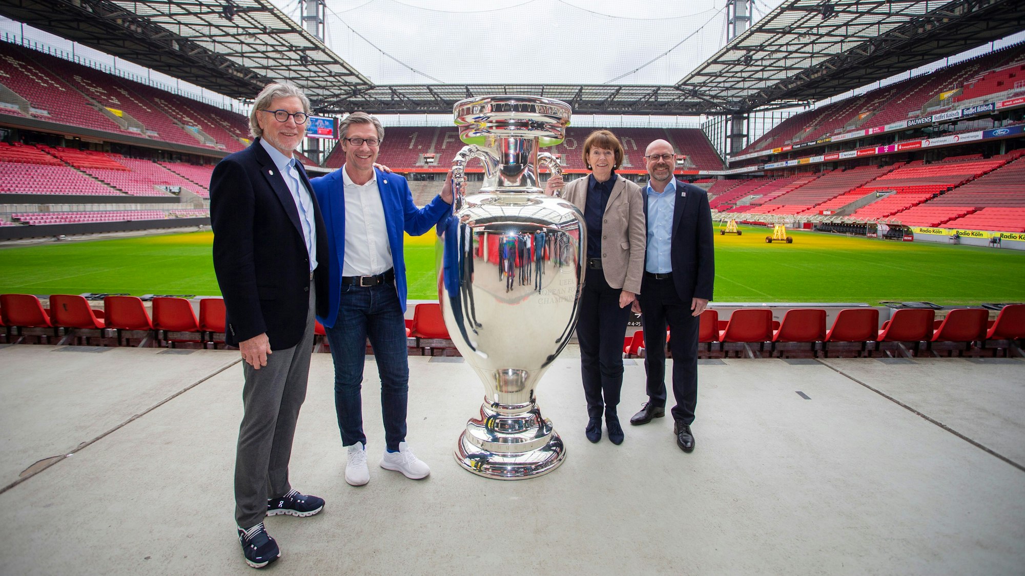 Das Größte: Die Fußball-EM überstrahlt das Kölner Sportjahr. Vorfruede herrscht bereits bei EM-Botschafter Toni Schumacher, Christos Katzidis (Präsident des Fußball-Verbandes Mittelrhein), Oberbürgermeisterin Henriette Reker und Sportstätten-Chef Lutz Wingerath. Die Personen stehen mit riesiger EM-Pokal-Attrappe im Rheinenergie-Stadion.