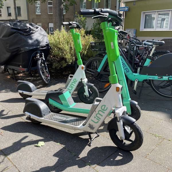 Mehrere E-Scooter stehen auf einem Gehweg.