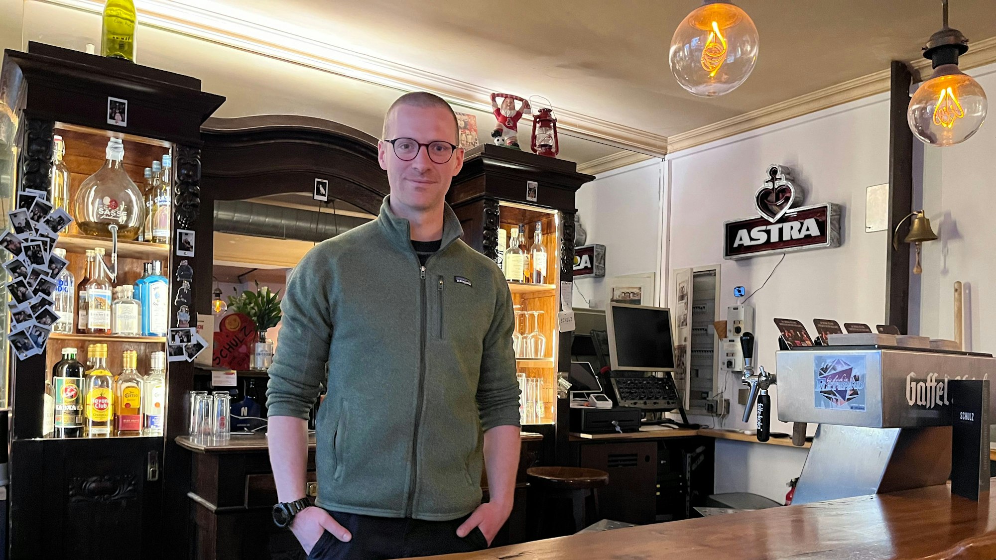 Ein Mann steht hinter der Theke in einer Kneipe.