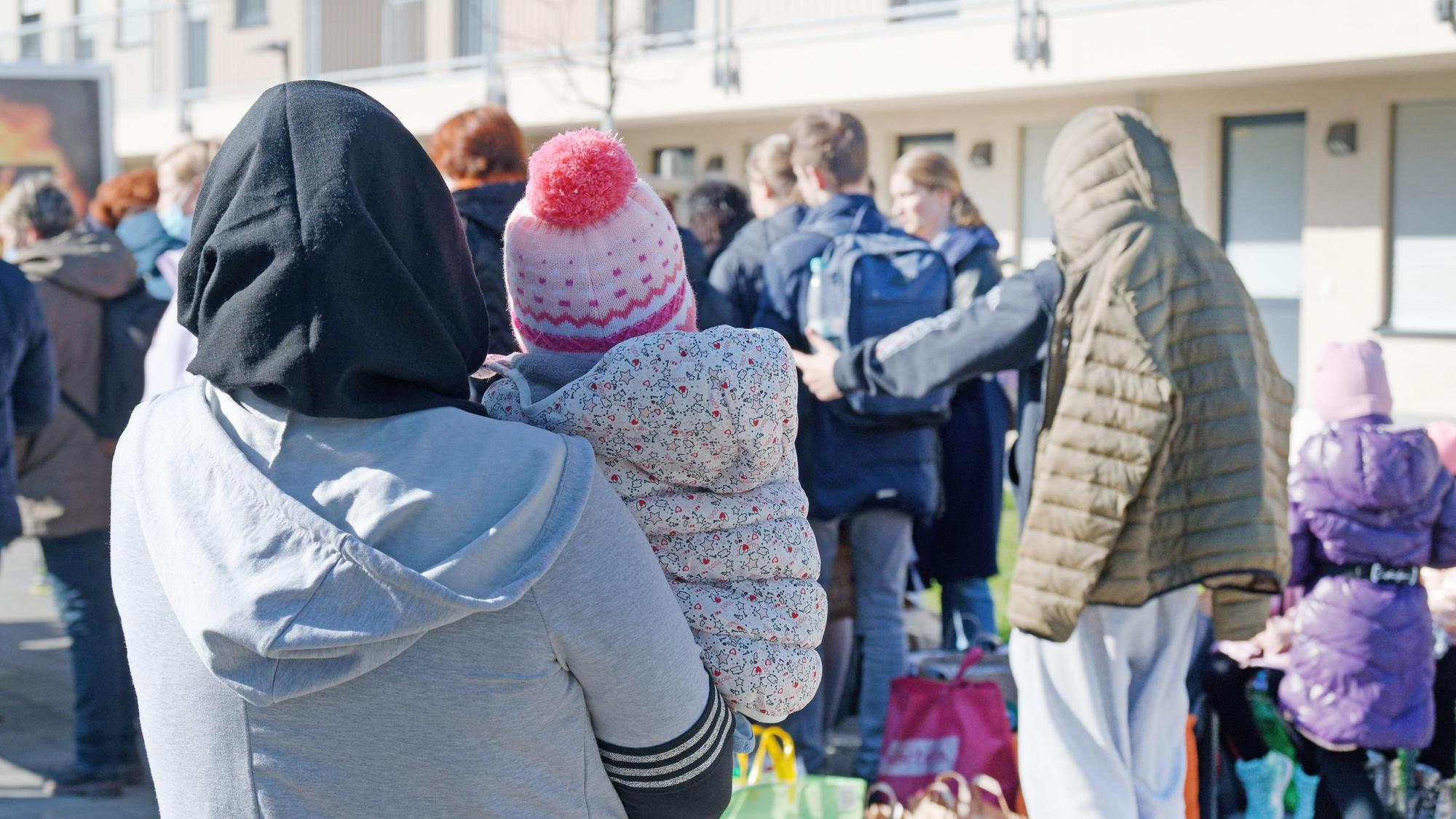Geflüchtete aus der Ukraine stehen vor den Gebäuden einer Flüchtlingsunterkunft.