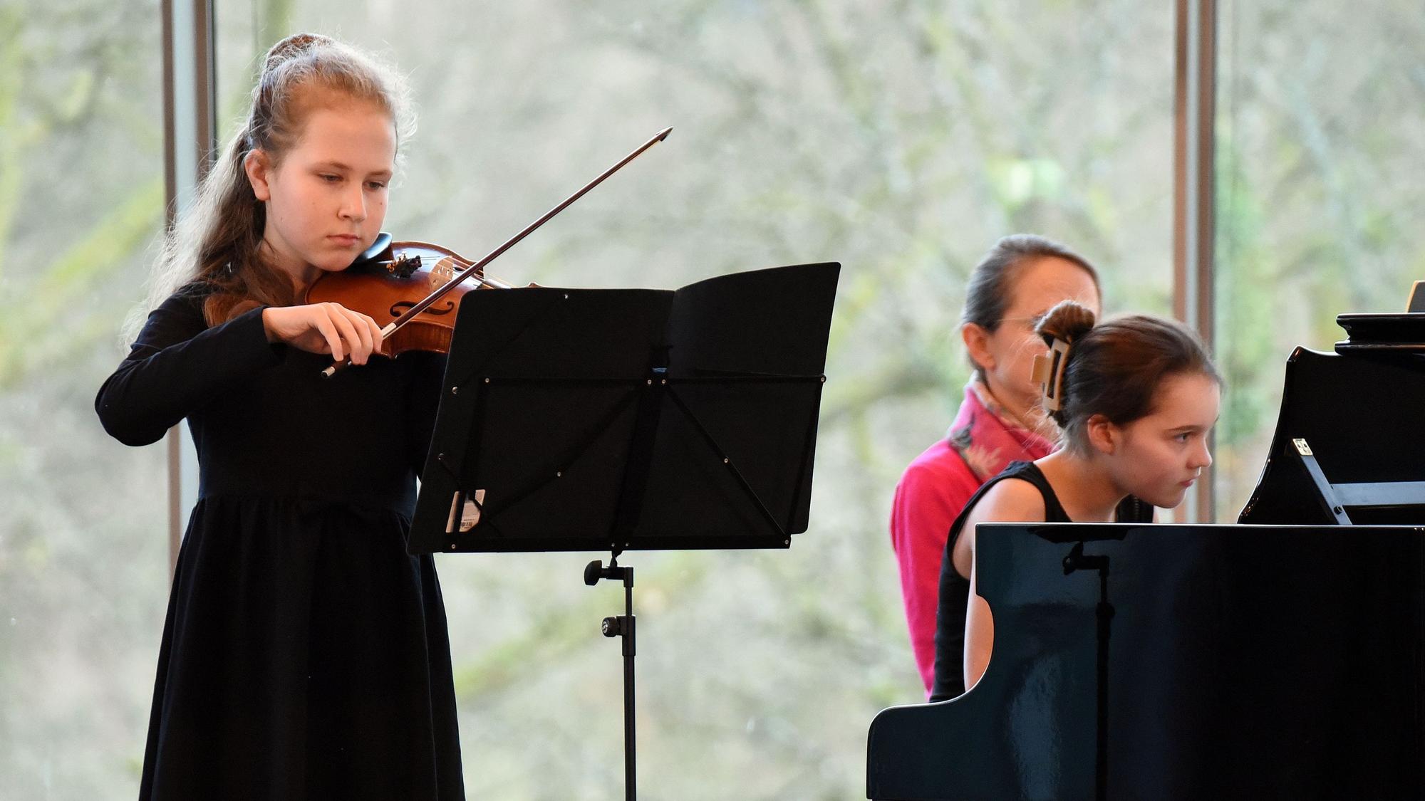 Ein Mädchen spielt Violine, ein weiteres Klavier.