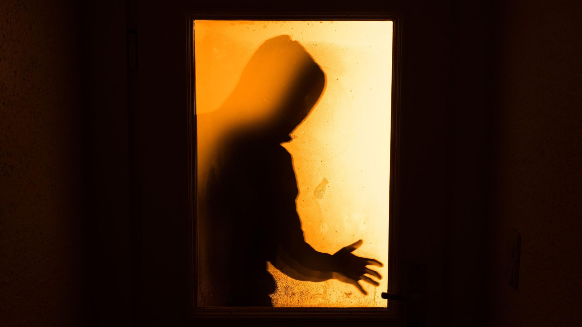 Das Bild zeigt eine Person hinter einer Glasscheibe.