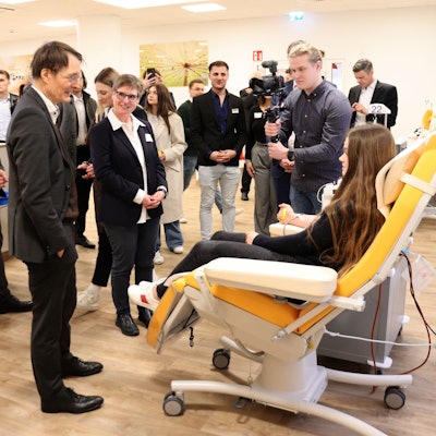 Einige Menschen stehen bei einer Frau, die auf einer Liege sitzt und Blutplasma spendet.