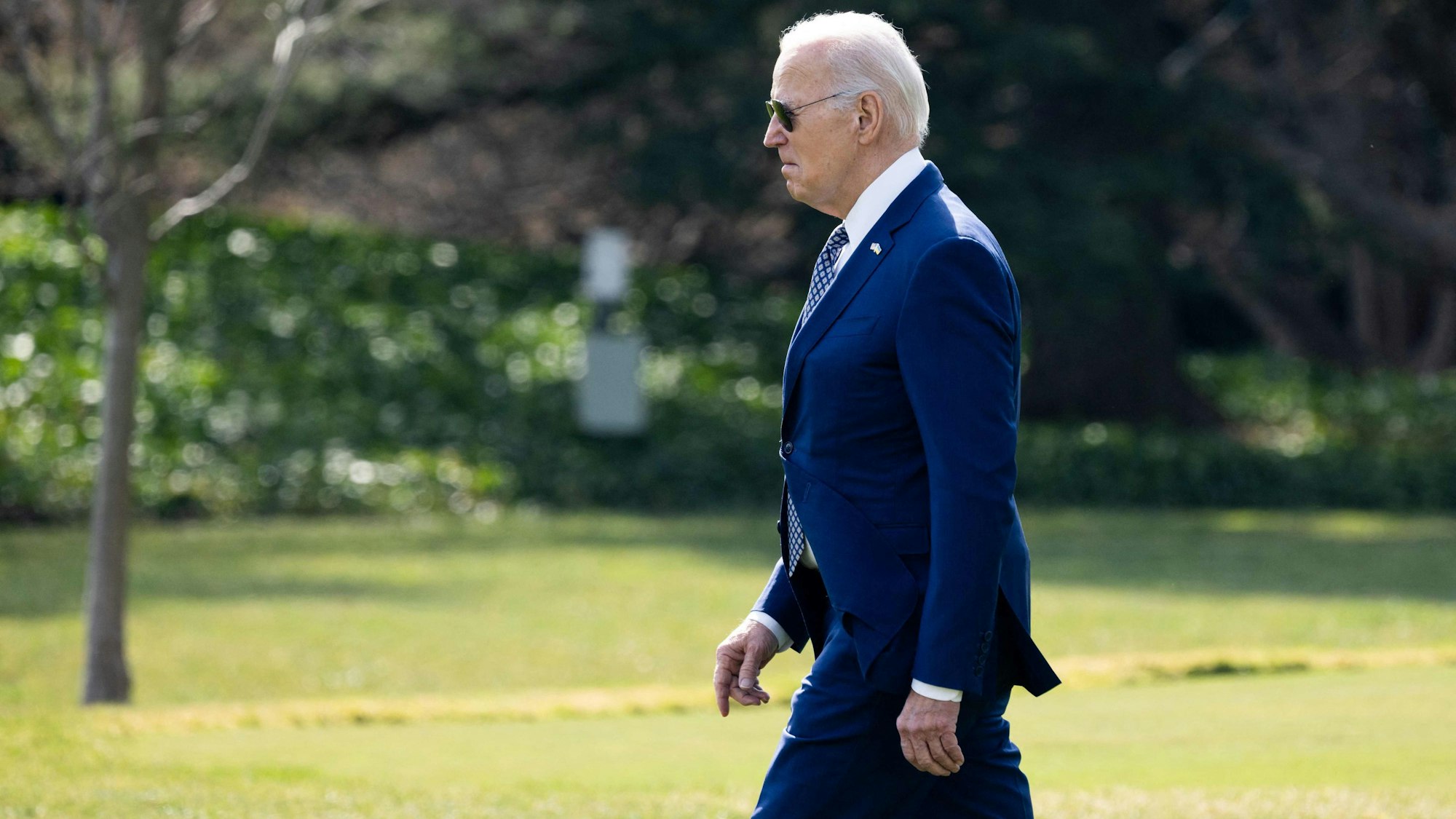 US-Präsident Joe Biden spaziert auf einer Wiese neben dem Weißen Haus.