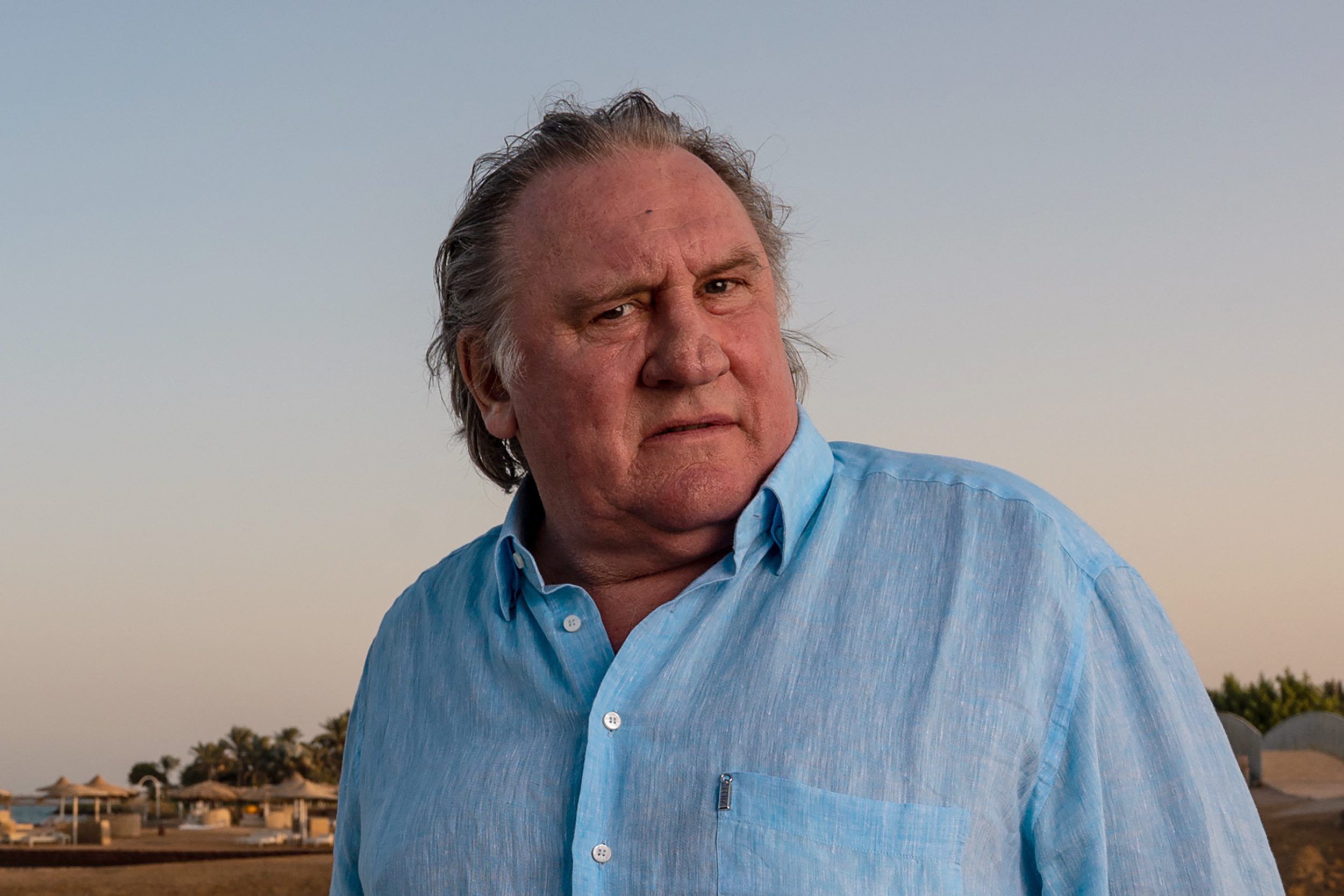 Filmstar Gérard Depardieu steht in einem blauen Hemd an einem Strand. (Archivbild)