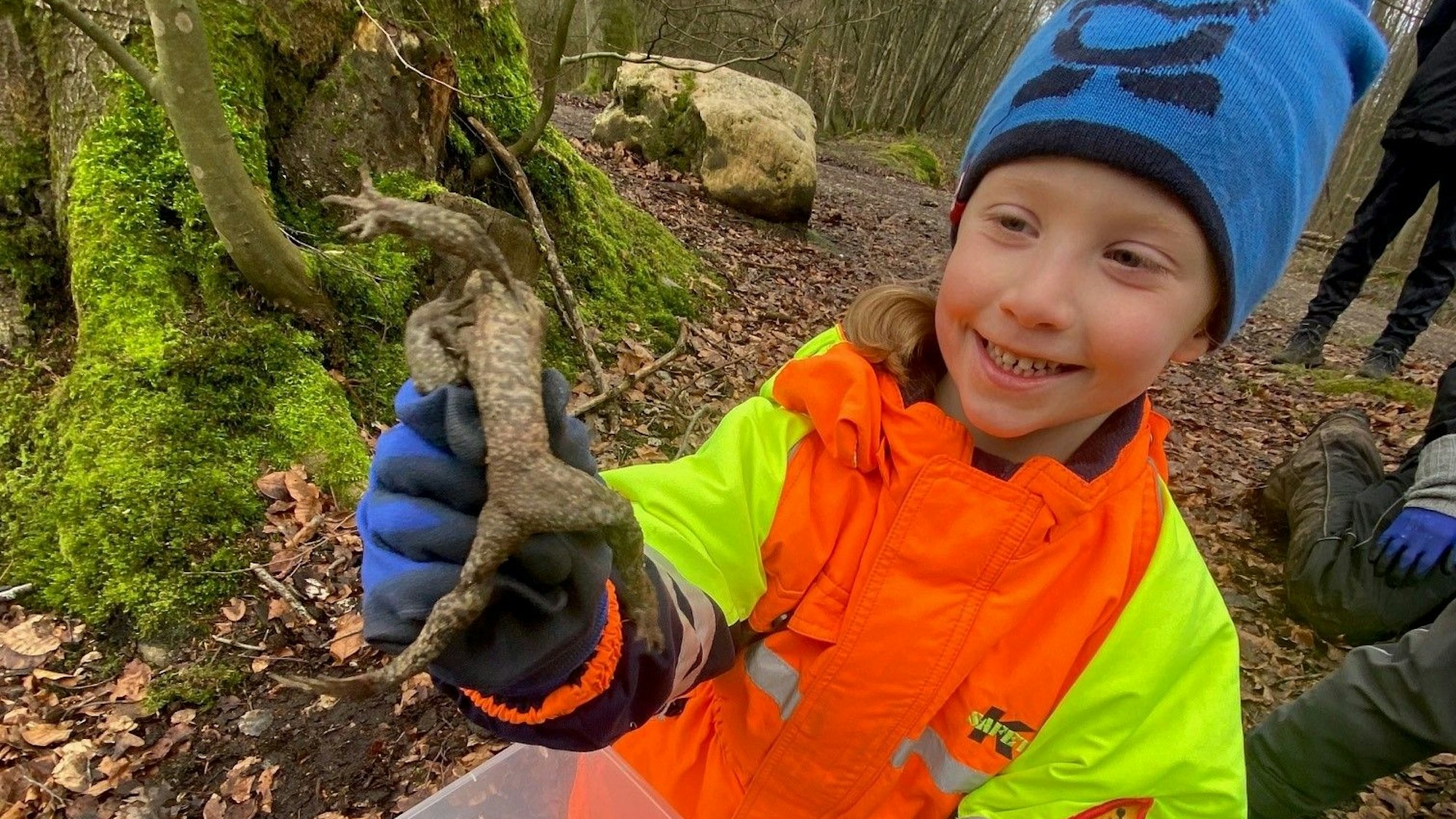 Auf dem Bild ist ein Mädchen mit einer Kröte zu sehen.
