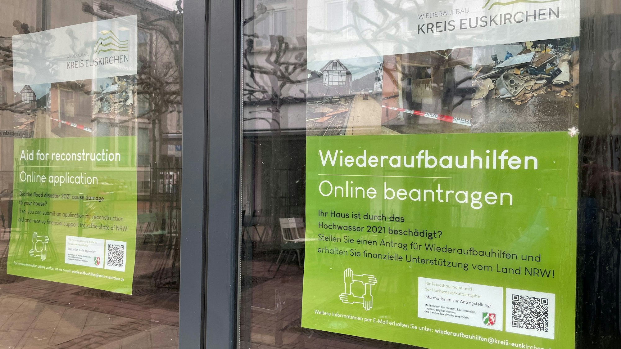 Das Bild zeigt zwei Plakate in einem Geschäft in Euskirchen. Sie weisen auf die Wiederaufbauhilfe des Landes hin.