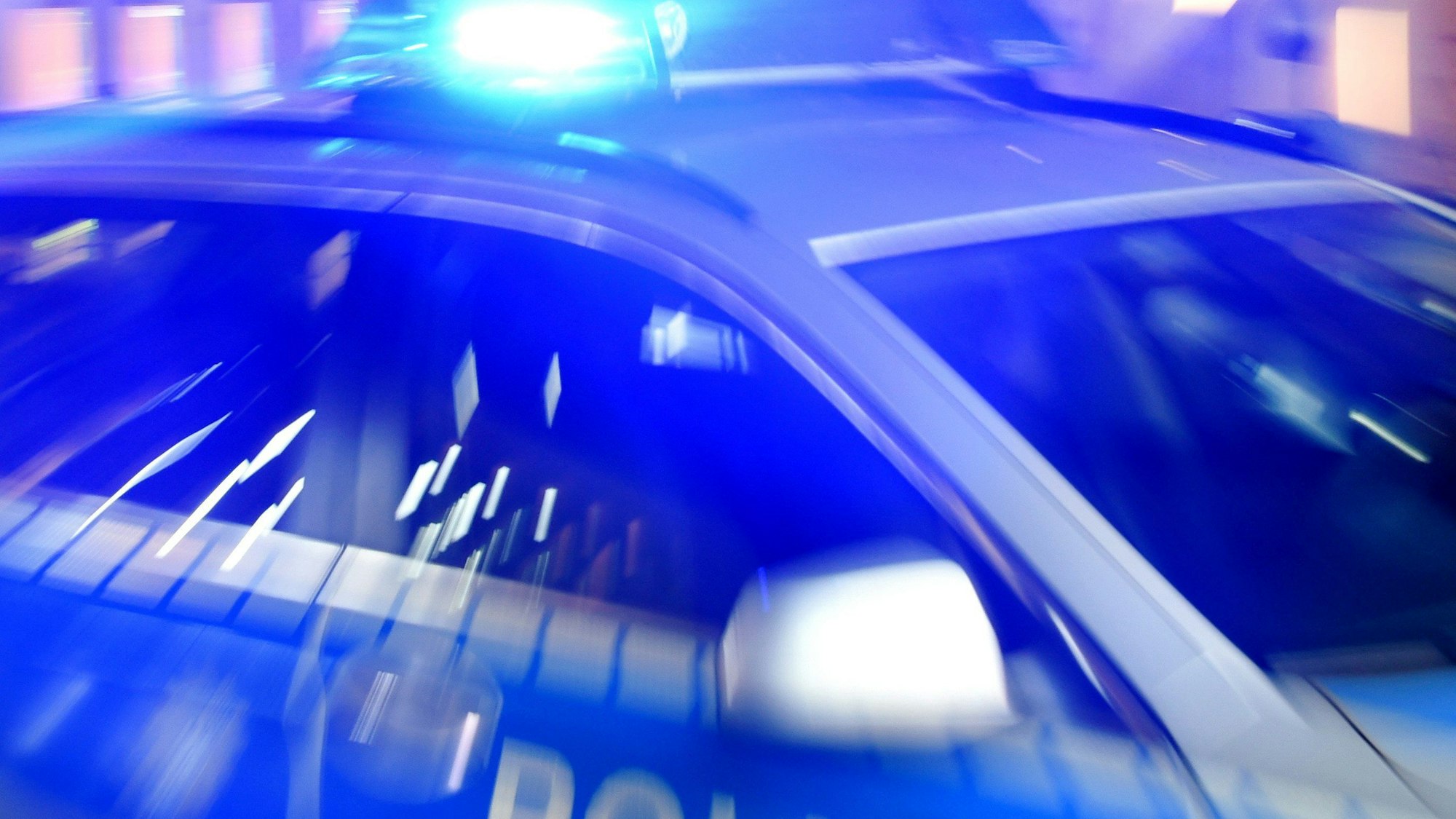 Ein Streifenwagen der Polizei steht mit eingeschaltetem Blaulicht auf der Straße.