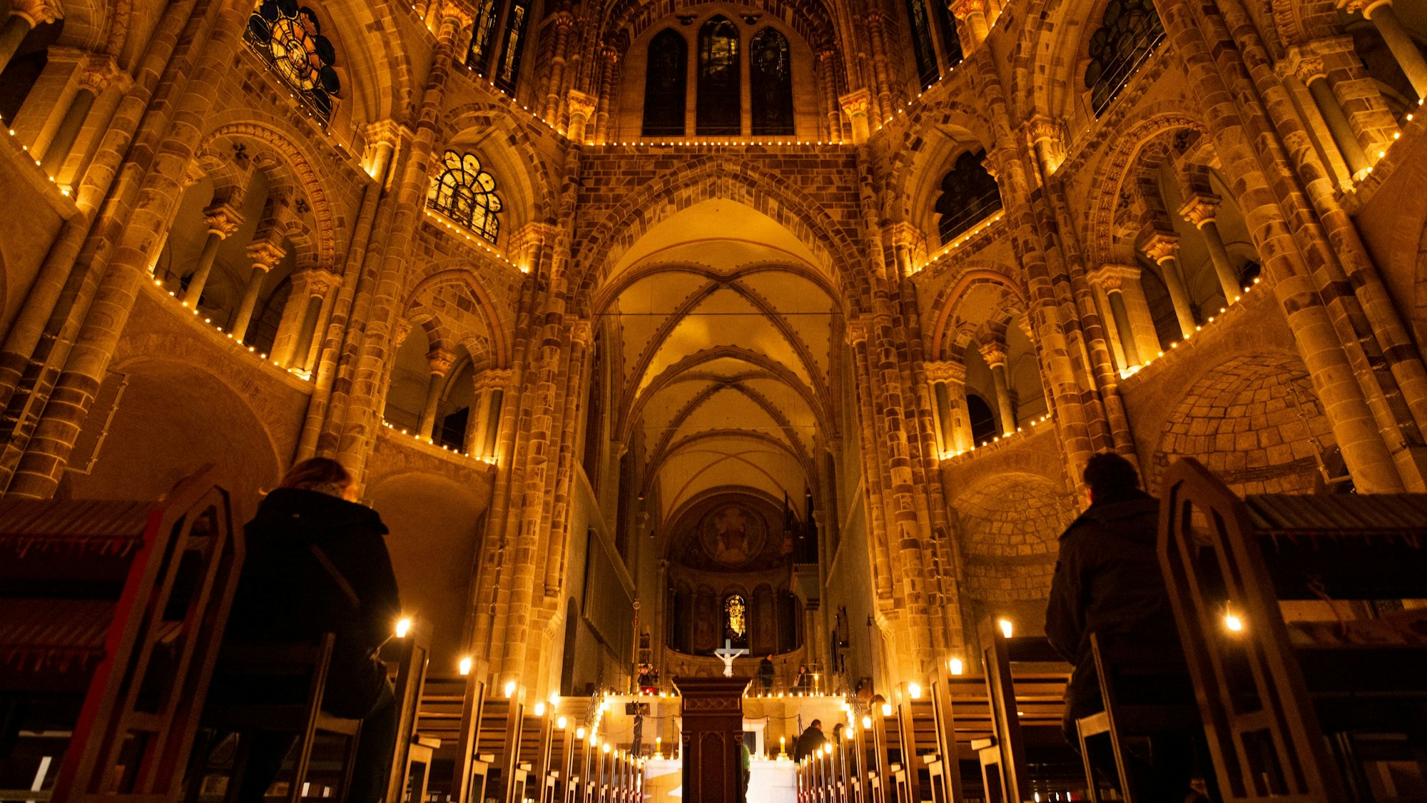 Der Innenraum einer Kirche leuchtet in einem warmen, orangefarbenen Licht.