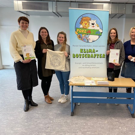 Junge und ältere Frauen stehen links und rechts von einem Aufsteller mit der Aufschrift Klimabotschafter.