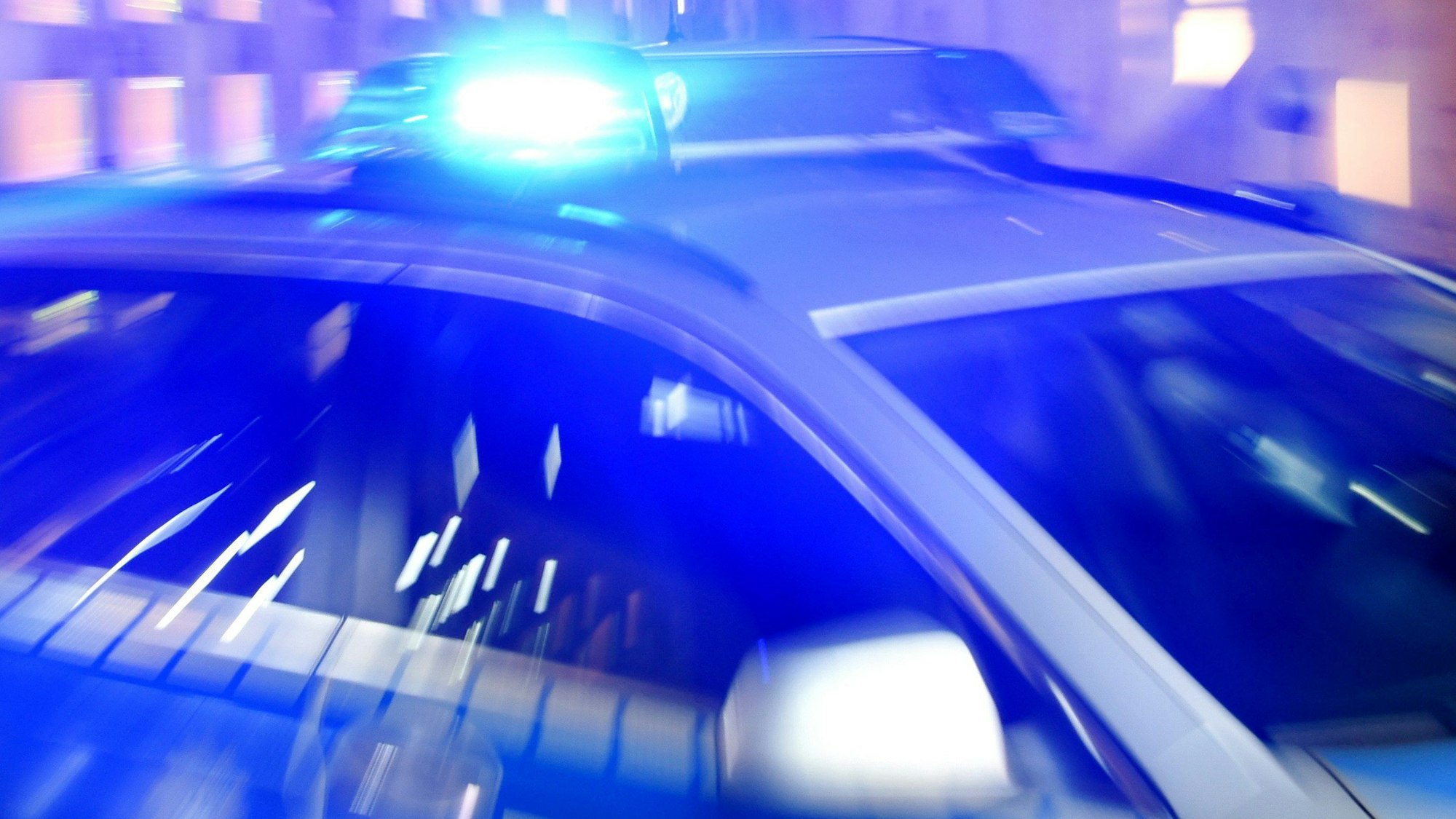 Ein Streifenwagen der Polizei steht mit eingeschaltetem Blaulicht auf der Straße.
