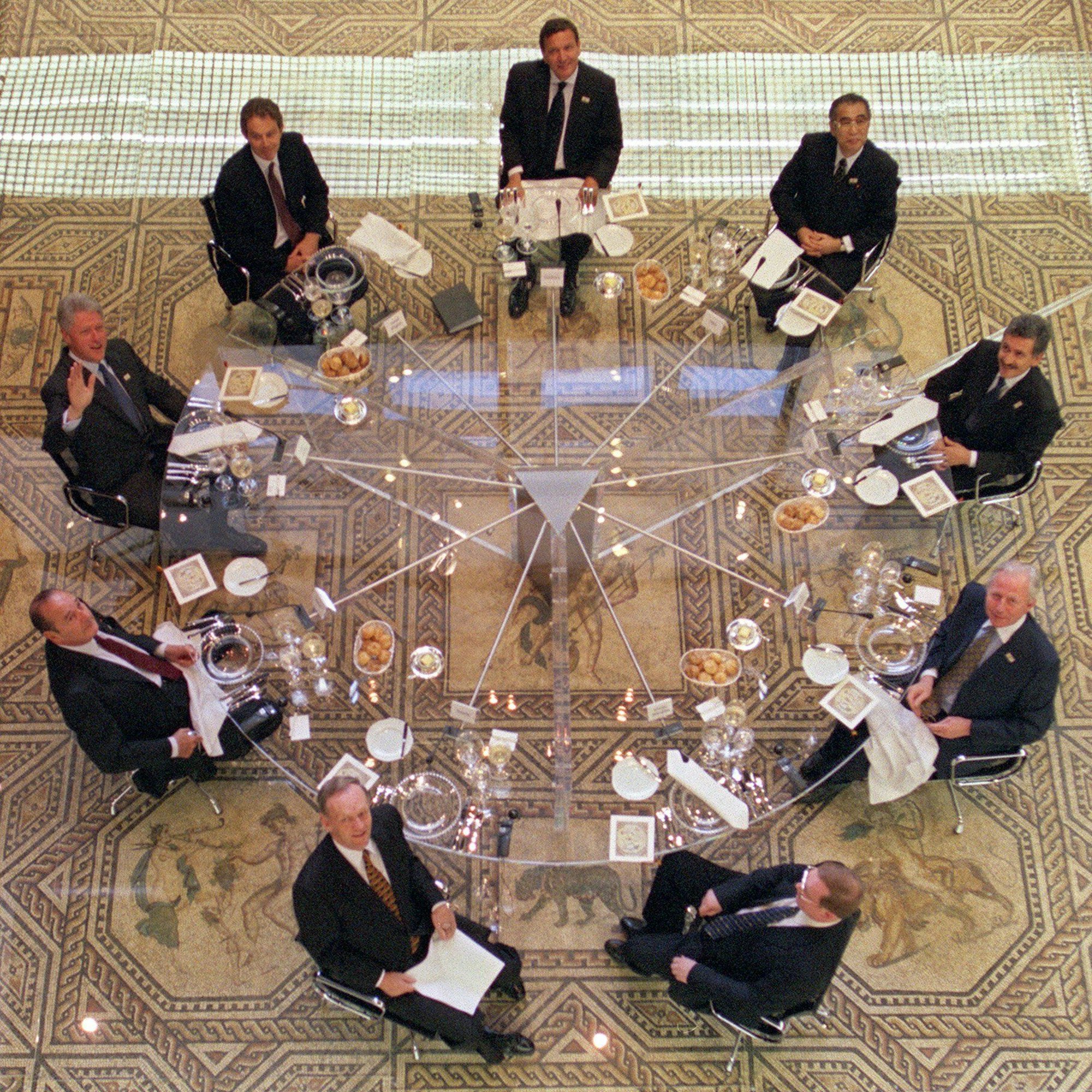 Zu Beginn des Arbeitsessens beim Kölner G-8-Gipfel auf dem Dionysos-Mosaik im Römisch-Germanischen Museum winkt am 18. Juni 1999 US-Präsident Bill Clinton (links) den Fotografen zu. Daneben (im Uhrzeigersinn) der britische Premierminister Tony Blair, Bundeskanzler Gerhard Schröder, der japanische Premierminister Keizo Obuchi, sein italienischer Amtskollege Massimo D'Alema, der scheidende EU-Kommissionspräsident Jacques Santer, der russische Regierungschef Sergej Stepaschin, der kanadische Premierminister Jean Chrétien und der französische Staatspräsident Jacques Chirac.