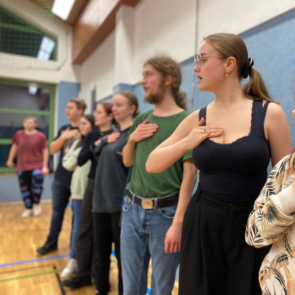 Die Schauspieler des Projekts „Spotlight Experience“ stehen in einer Reihe und halten ihr Hand auf die Brust