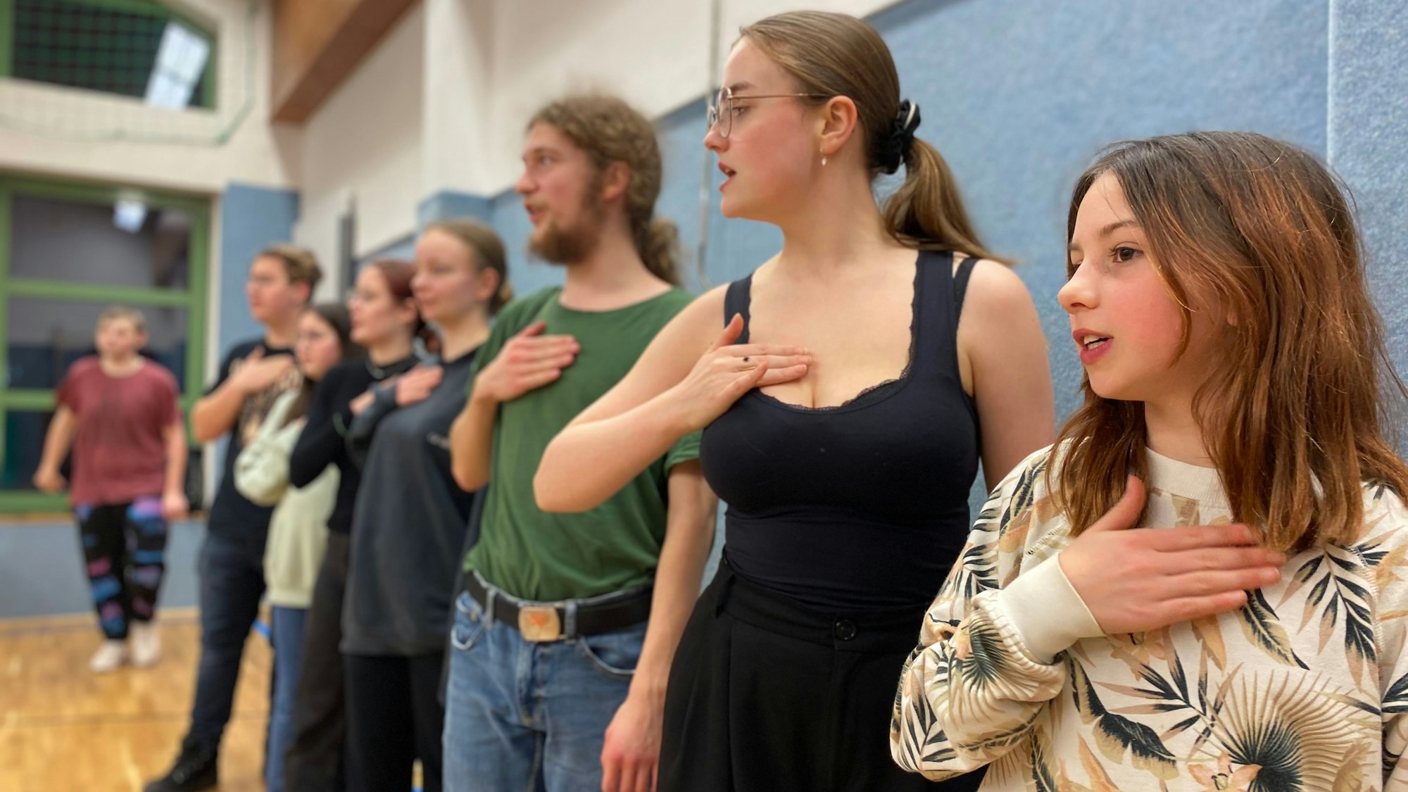 Die Schauspieler des Projekts „Spotlight Experience“ stehen in einer Reihe und halten ihr Hand auf die Brust