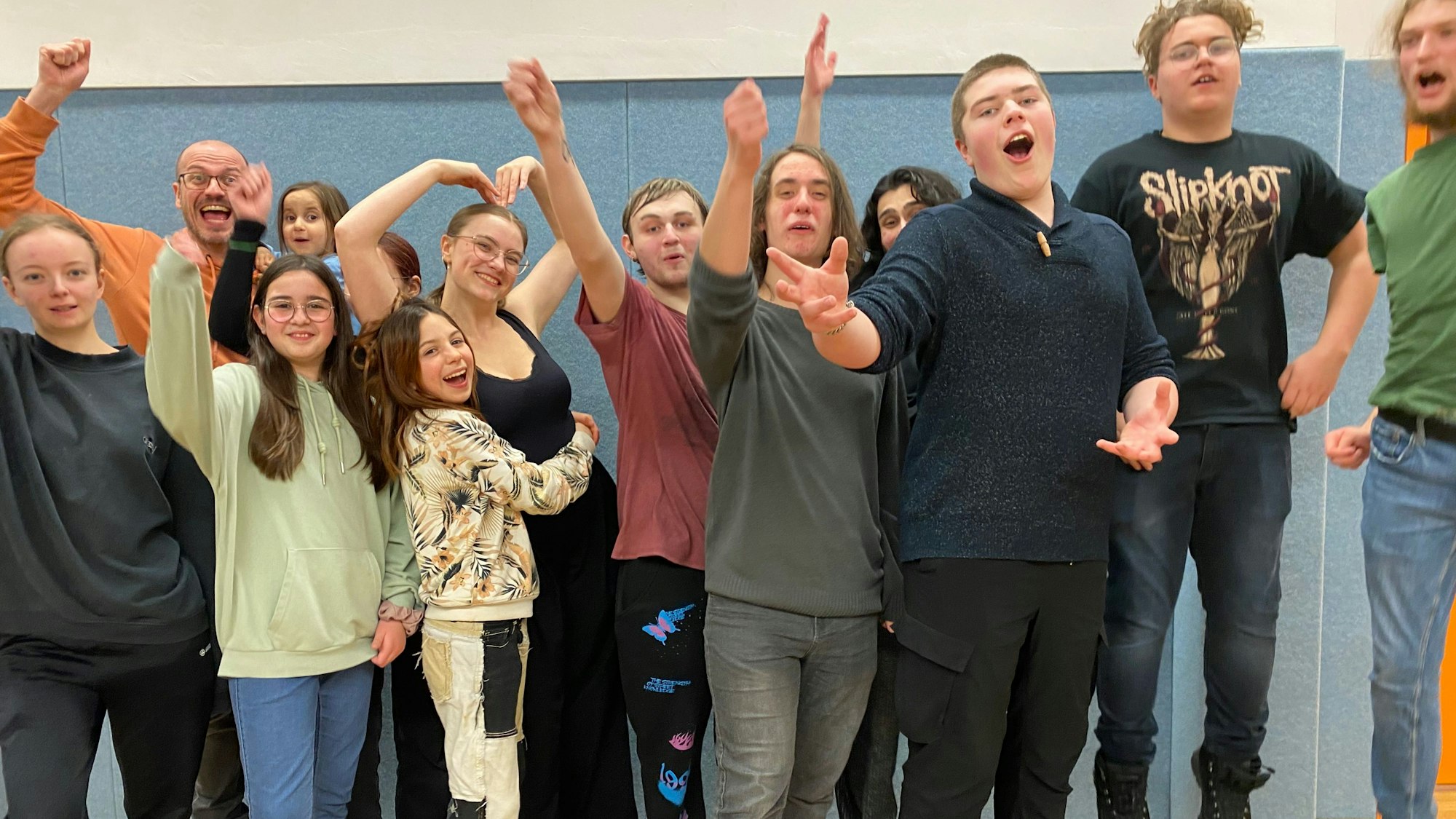Ein Gruppenbild der Schauspieler der Theatergruppe Spotlight Experience: Die jungen Leute freuen sich und recken ihre Arme in die Luft.