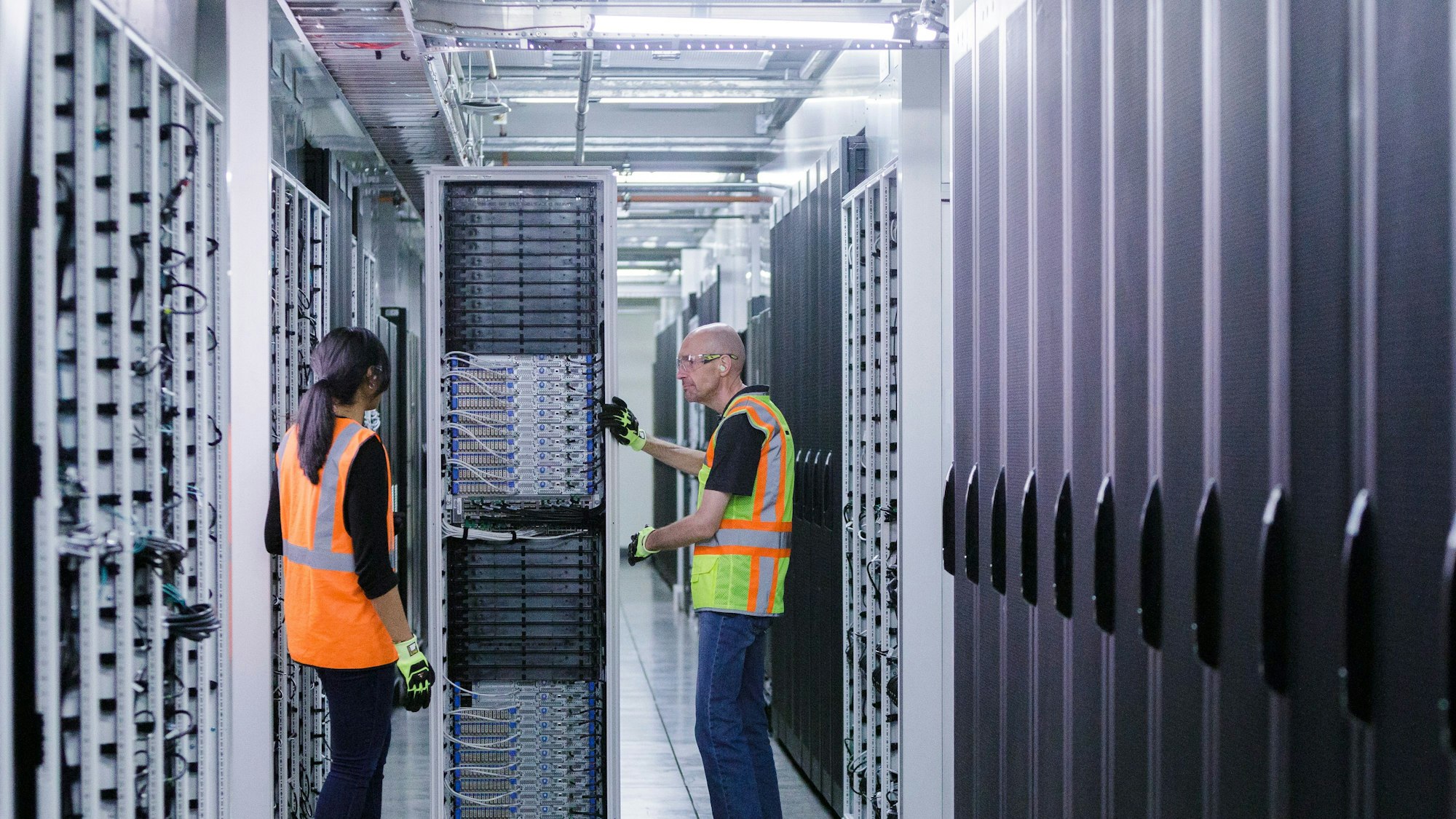Blick in ein Rechenzentrum, zwei Personen sind umgeben von Servern.