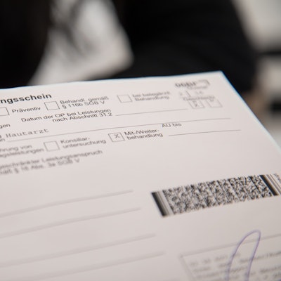 Zwei Finger zeigen auf einen Überweisungsschein.