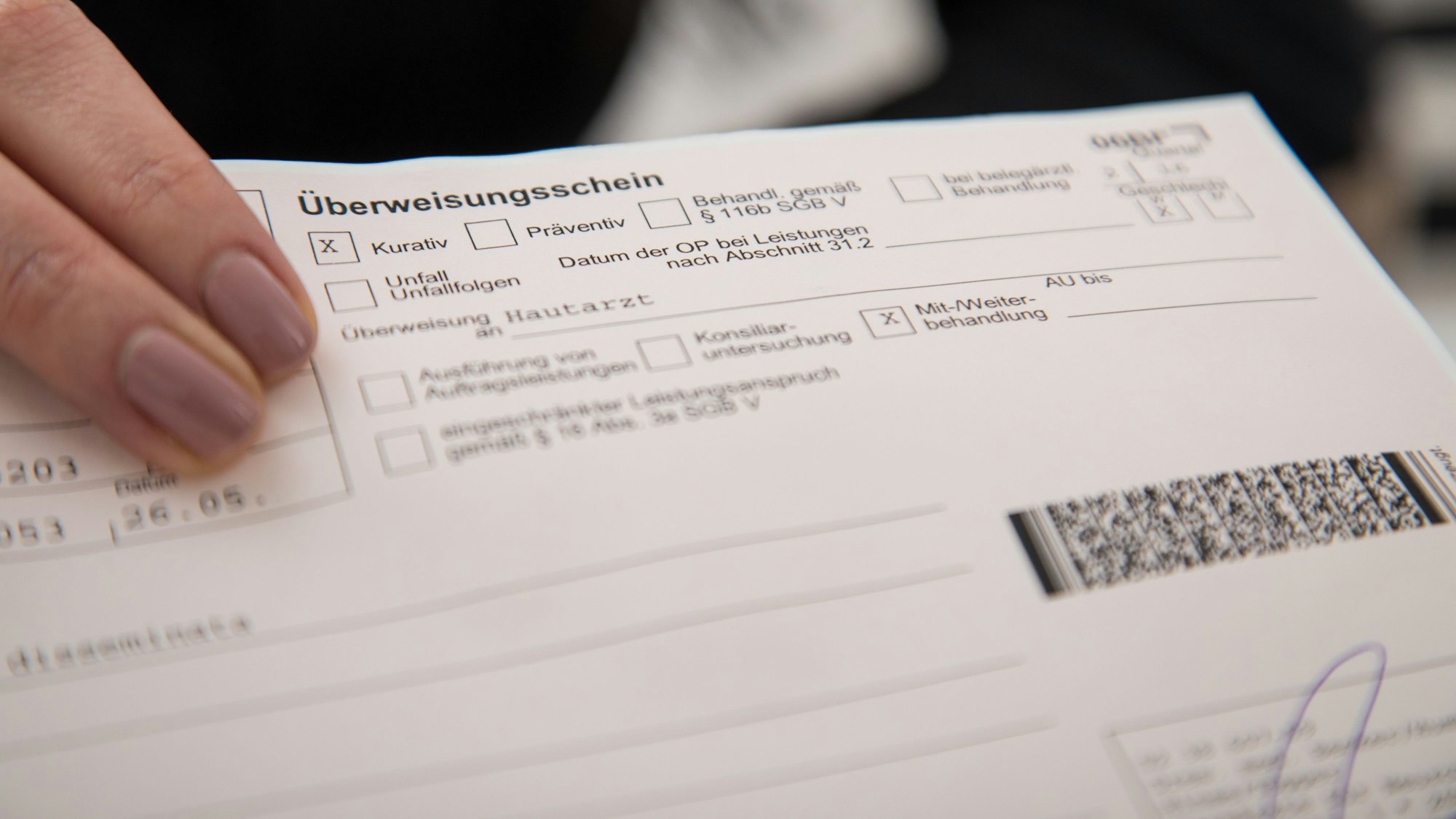 Zwei Finger zeigen auf einen Überweisungsschein.