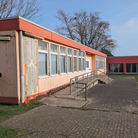 Ein maroder Pavillon mit abgeblätterter Farbe an der Fassade auf dem Schulhof der Martinusschule in Fischenich.
