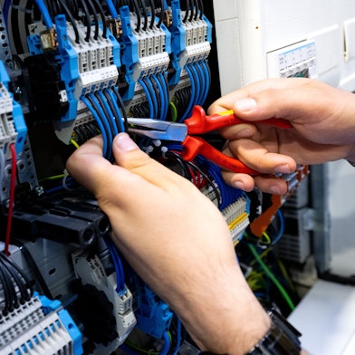 Ein Mann arbeitet bei einem Rundgang über die Internationale Handwerksmesse (IHM) an einem Messestand an einem Stromkasten.