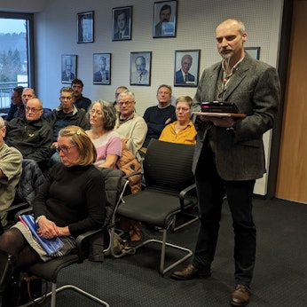 Eine Gruppe Bürger aus Kallmuth sitzt im Sitzungssaal des Mechernicher Rathauses. Ein Mann steht und hält Akten in der Hand.