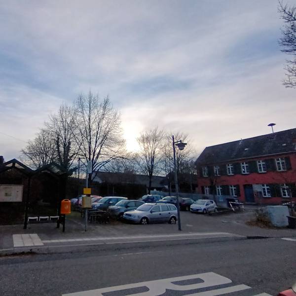 Eine Kirche und ein altes Gebäude, dazwischen ein Parkplatz