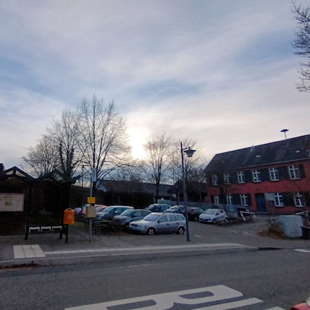 Eine Kirche und ein altes Gebäude, dazwischen ein Parkplatz