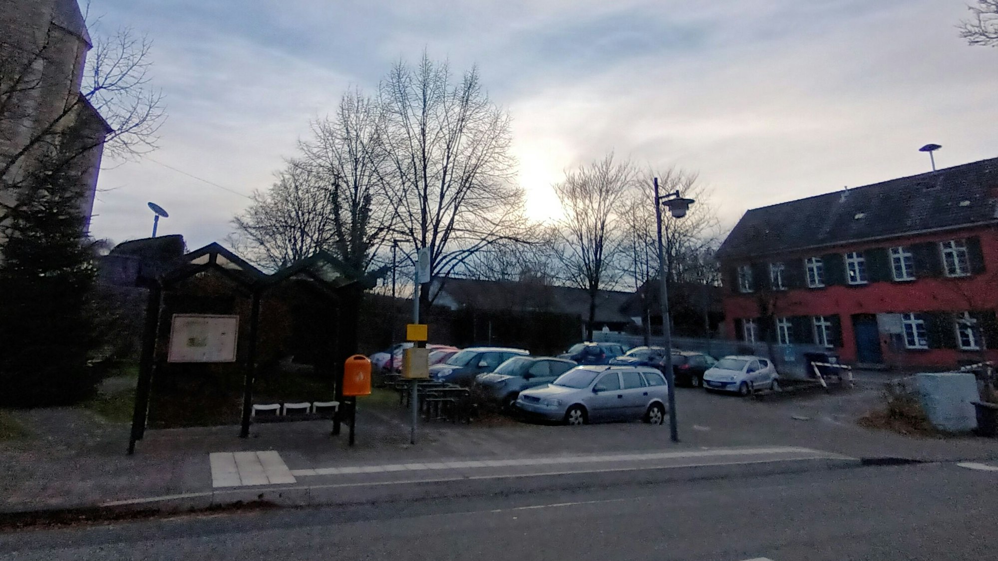 Ein altes Gebäude und eine Kirche, dazwischen ein Parkplatz