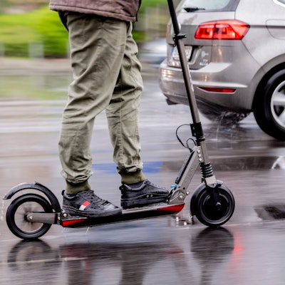 Ein Mann fährt mit einem E-Scooter auf der Straße.