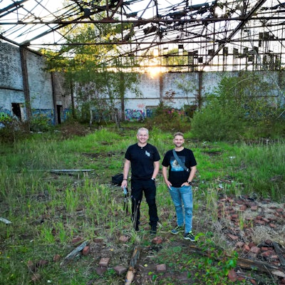 Zwei Männer stehen in einem alten Fabrikgebäude.