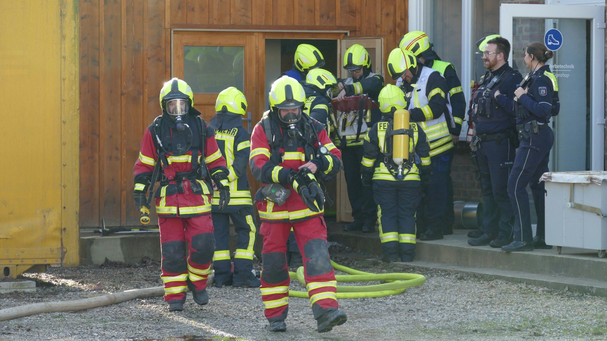 Feuerwehrleute unter Atemschutz verlassen ein Gebäude.