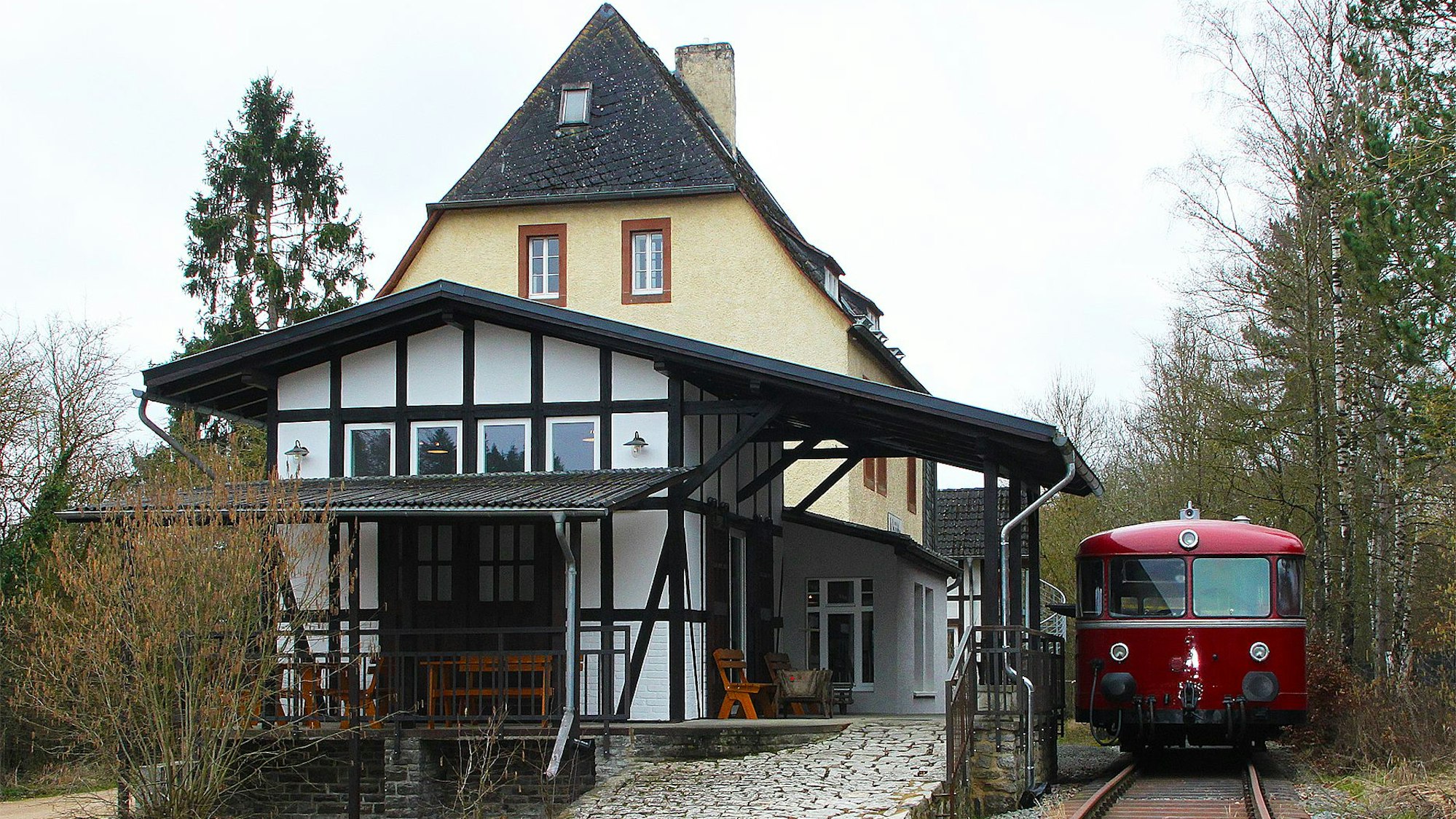 Neben dem Gebäude des Museumsbanhnhofs steht ein roter Schienenbus auf den Gleisen.