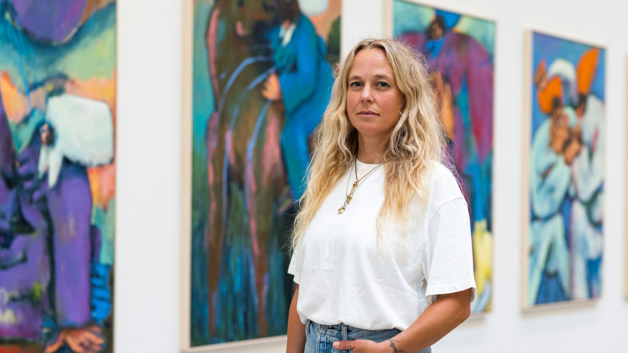 Eine Frau steht vor einer Wand mit Kunstwerken.