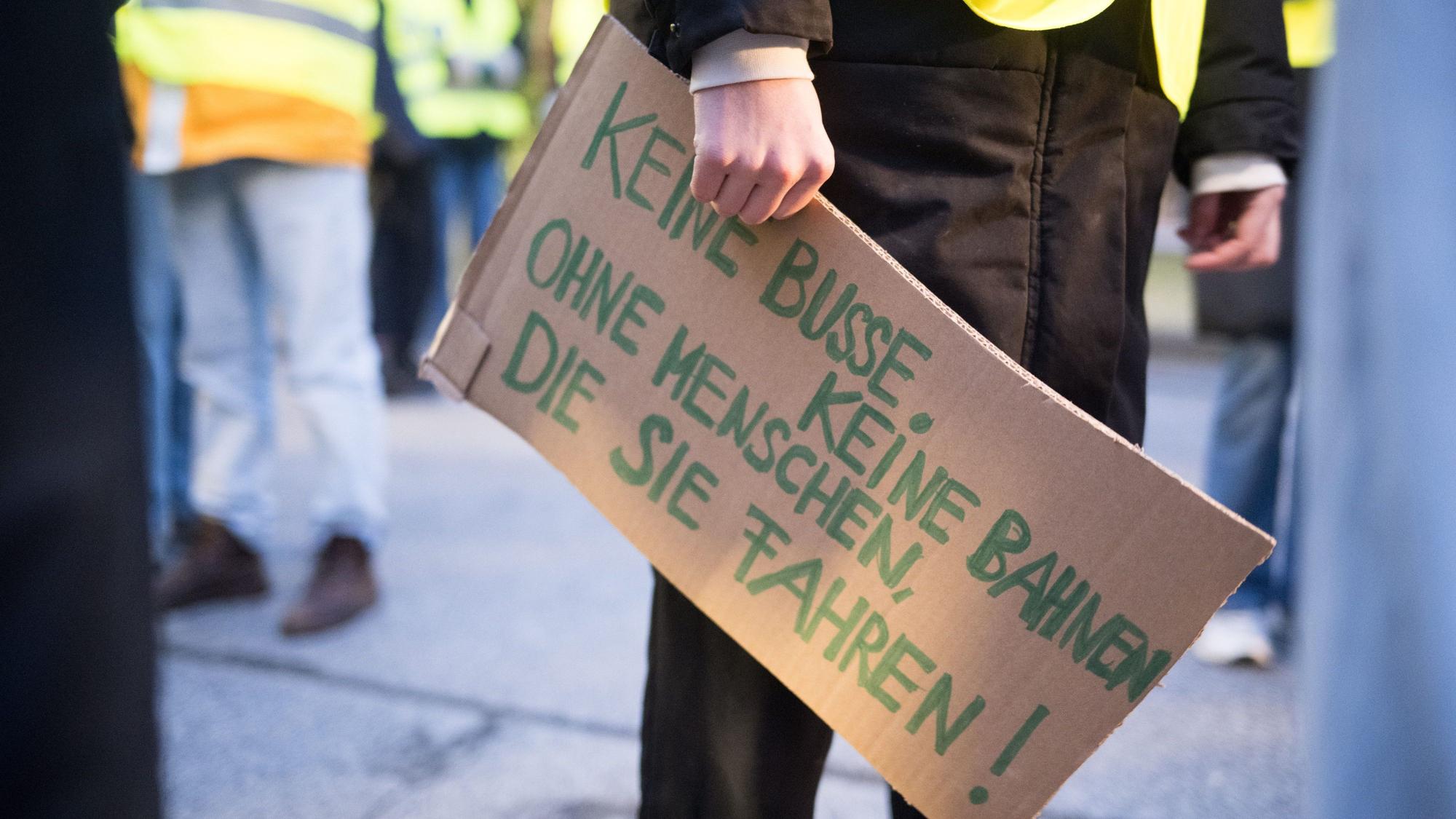 Luisa Neubauer, Aktivistin von Fridays for Future, hält am BVG-Busdepot Cicerostraße ein Schild mit der Aufschrift «keine Busse, keine Bahnen, ohne Menschen, die sie fahren!» in der Hand.