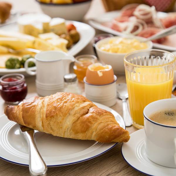 Ein Frühstückstisch mit Kaffee, Orangensaft, einem hartgekochten Ei und verschiedenem Aufschnitt. (Symbolbild)